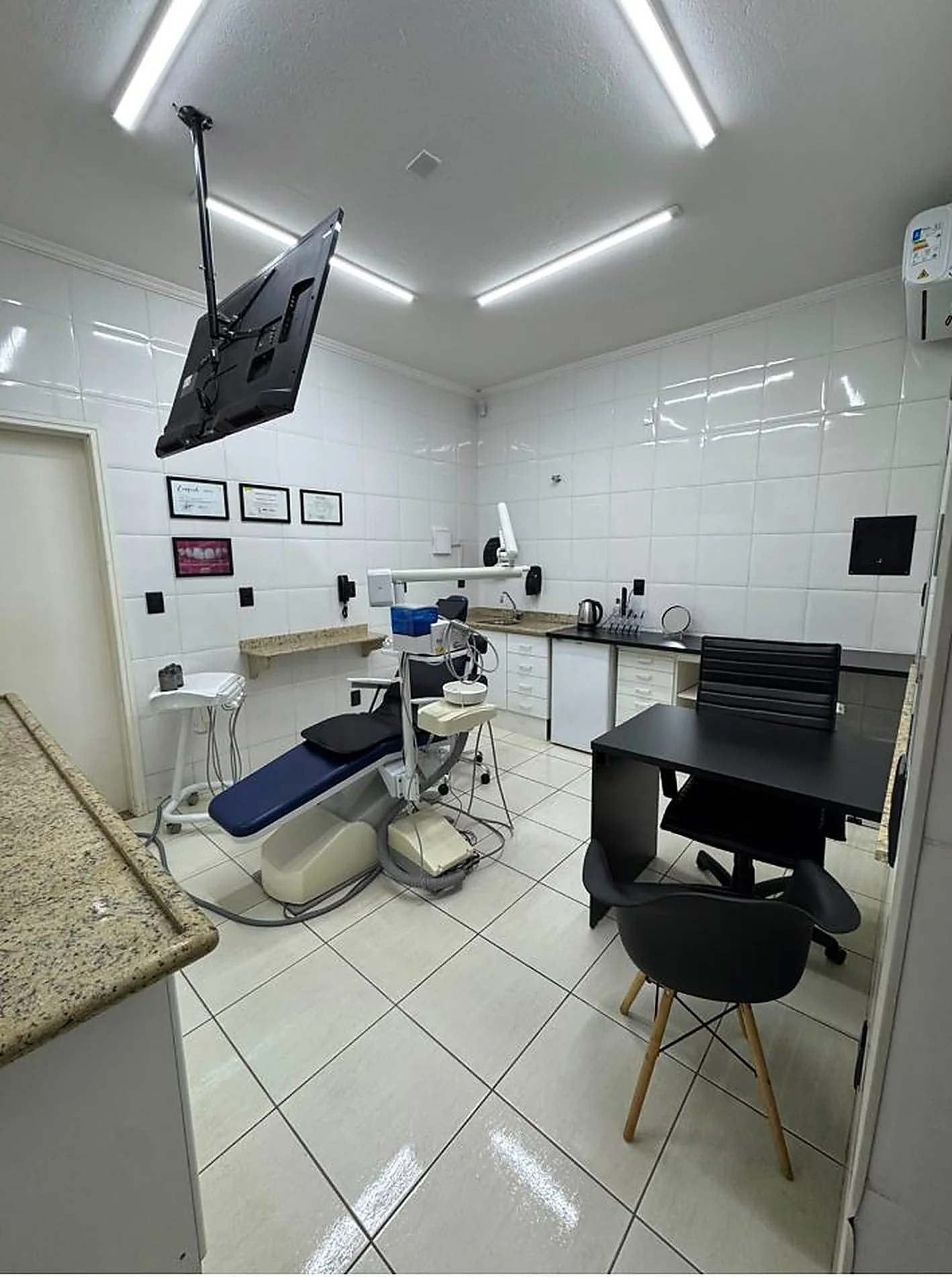 Sala de atendimento do consultório, com cadeira odontológica e bancada